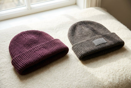 Two custom beanies side by side, one with direct embroidery and one with a stitched fabric patch on the cuff