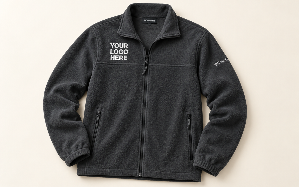 Charcoal Columbia fleece jacket with white YOUR LOGO HERE on the right chest above its horizontal seam.