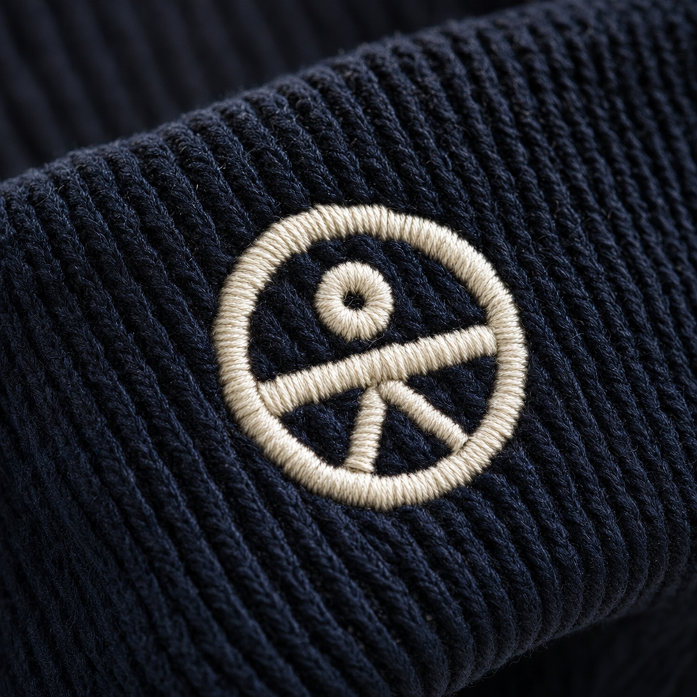 Close-up of an embroidered logo stitched into a ribbed knit beanie cuff