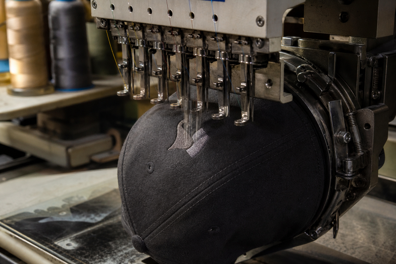 An embroidery machine stitching a logo onto a cap