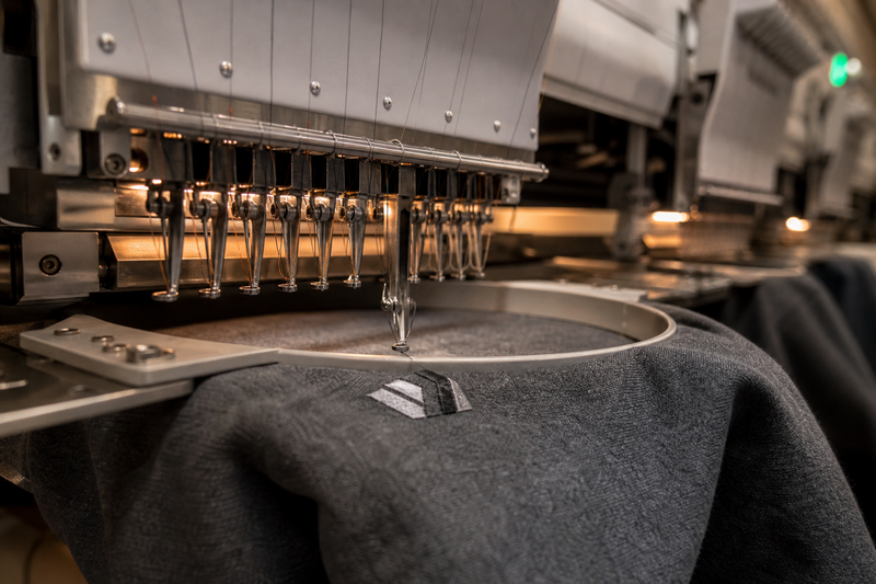 An embroidery machine stitching a logo onto a crewneck sweatshirt
