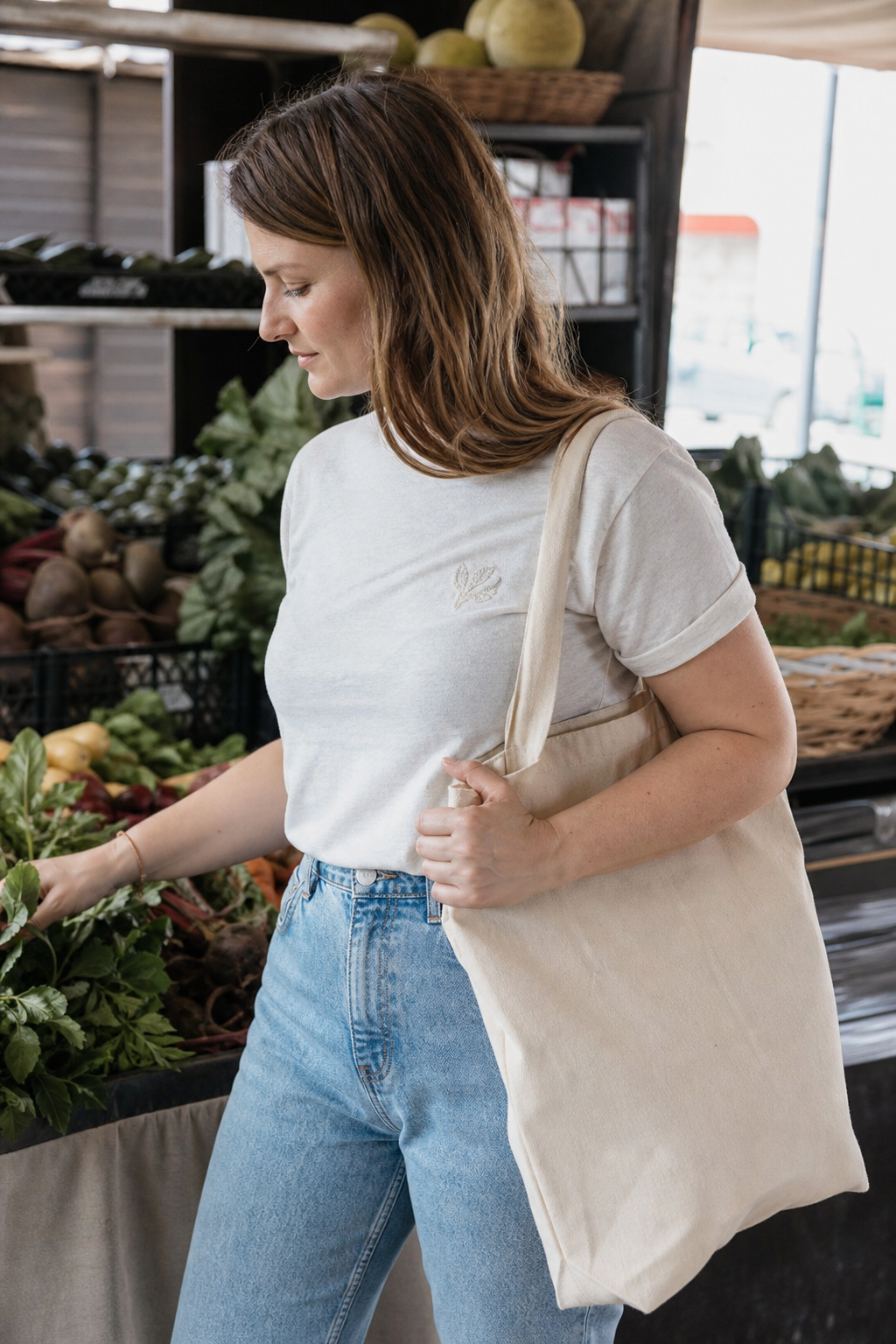 A boutique owner wearing a custom embroidered tote bag